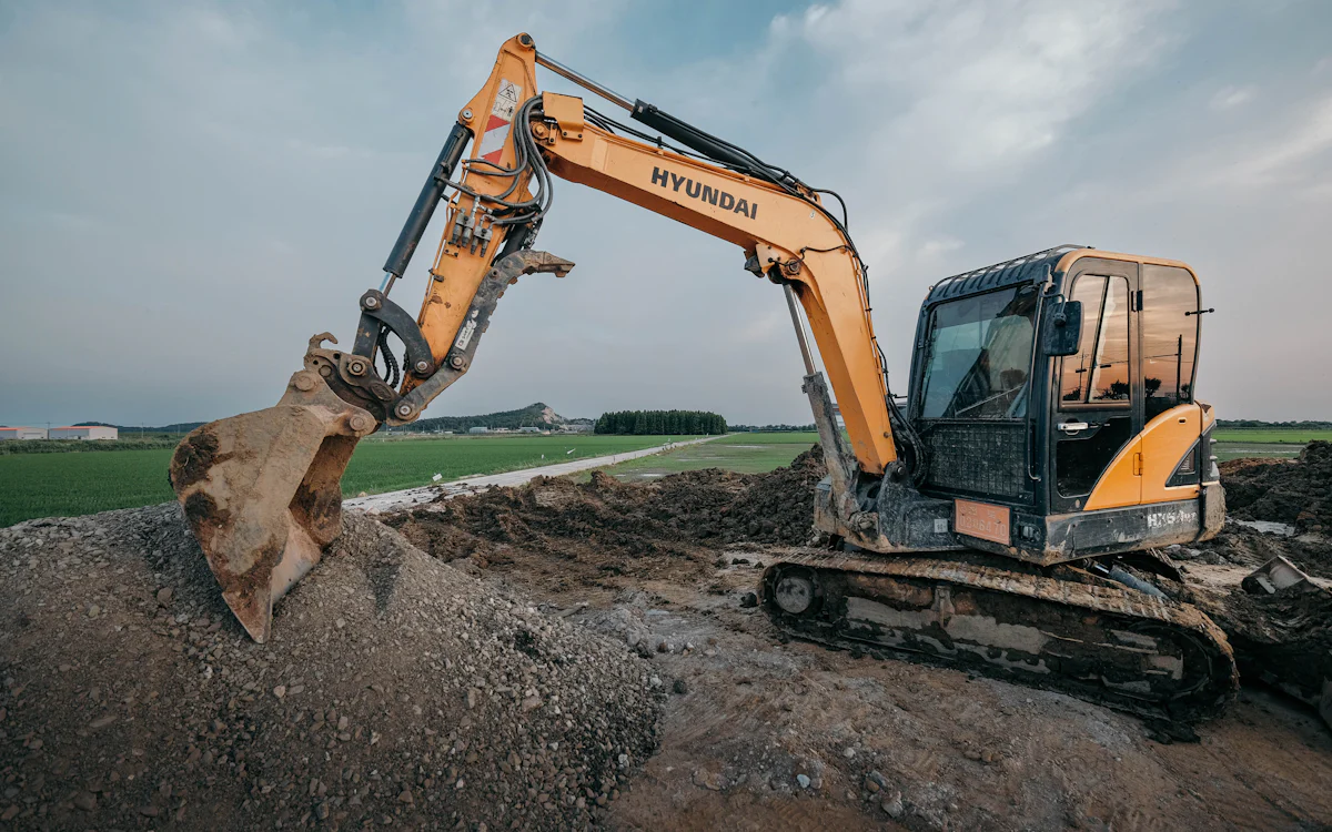 Excavator digging a trench on open ground